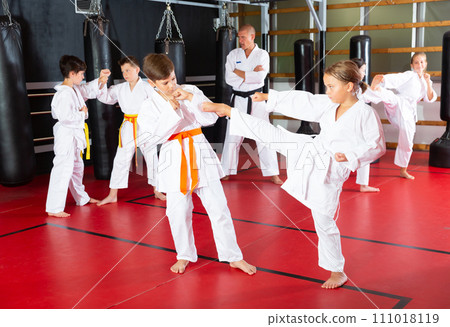 Kids working in pair, mastering kicks in karate class 111018119
