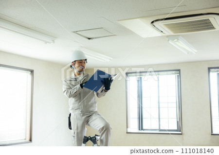 一名穿著工作服的男子正在檢查天花板 一名穿著工作服的男子正在檢查天花板 111018140