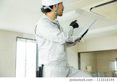 一名穿著工作服的男子正在檢查天花板 一名穿著工作服的男子正在檢查天花板 111018144