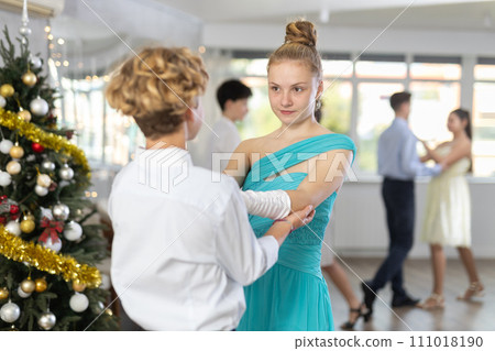 Teen boy and girl dancing waltz in couple during lesson at studio in New Year atmosphere 111018190