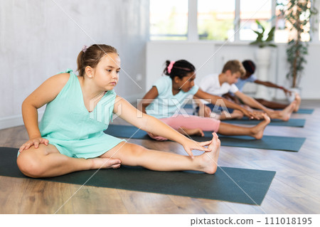 Young girl doing yoga in group of children Young girl doing yoga in group of children 111018195