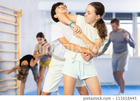 Preteen children pairs learning strength self-defense in gym 111018445