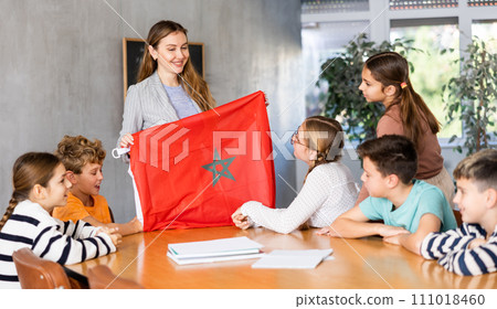 Female teacher shows scholchildren national flag of Morocco 111018460