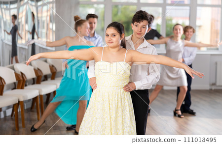 Positive teen boy and girl are dancing classic version of waltz in couple during lesson at studio Positive teen boy and girl are dancing classic version of waltz in couple during lesson at studio 111018495