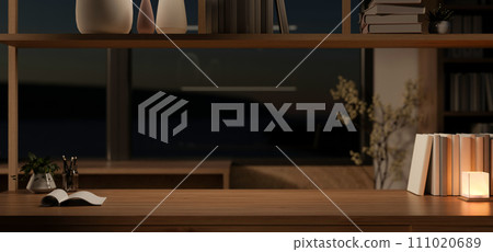 Cosy home office at night with a copy space on a wooden table and dim light from a table lamp. Cosy home office at night with a copy space on a wooden table and dim light from a table lamp. 111020689