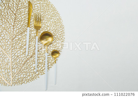 The food utensils, gold with a white handle, lie on a gold napkin on a white background. The concept of eating, the concept of serving. High quality photo 111022076
