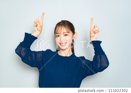 A woman pointing upwards with both hands A woman pointing upwards with both hands 111022302