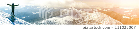 Silhouette of alone tourist standing on snowy mountain top in winner pose with raised hands enjoying view and achievement on bright sunny winter day. Adventure, outdoors activities, healthy lifestyle. Silhouette of alone tourist standing on snowy mountain top in winner pose with raised hands enjoying view and achievement on bright sunny winter day. Adventure, outdoors activities, healthy lifestyle. 111023007
