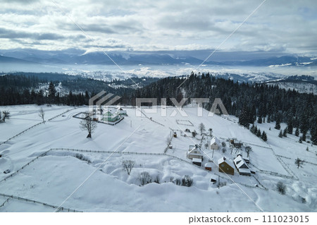 Winter landscape with small rural houses in remote settlement between snow covered forest in cold mountains Winter landscape with small rural houses in remote settlement between snow covered forest in cold mountains 111023015