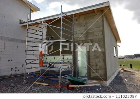 Facade of white block building under construction works. Facade of white block building under construction works. 111023087
