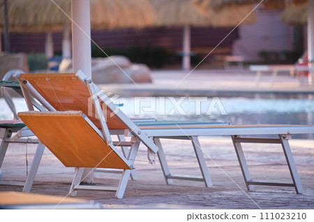 Empty deck chair on swimming pool side in summer resort. Vacations and getaway concept 111023210