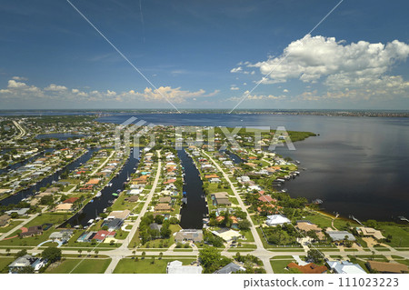 Aerial view of residential suburbs with private homes located on gulf coast near wildlife wetlands with green vegetation on sea shore. Living close to nature concept 111023223