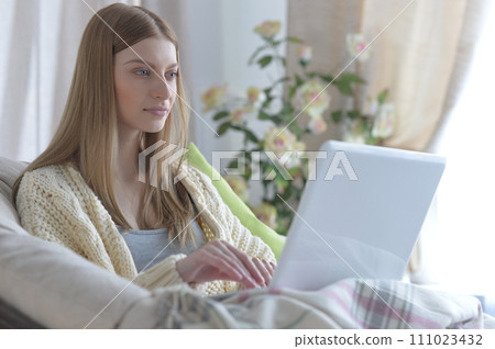 Portrait of young woman using laptop at home 111023432