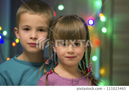 Family portrait of two young happy cute blond children, handsome boy and girl with lot of long braids, brother and sister smiling shyly together on colorful bokeh background. Happy childhood concept. 111023465
