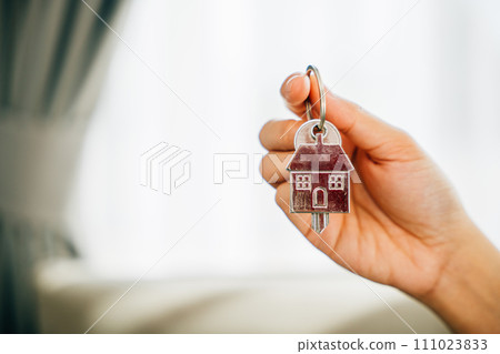 A female hand displays a house key symbolizing confidence and success in homeownership. Reflecting happiness achievement and the excitement of a new investment. 111023833