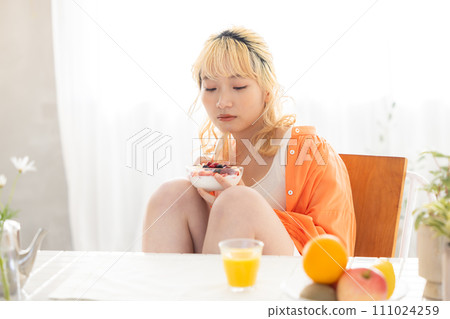 young blonde woman eating yogurt 111024259