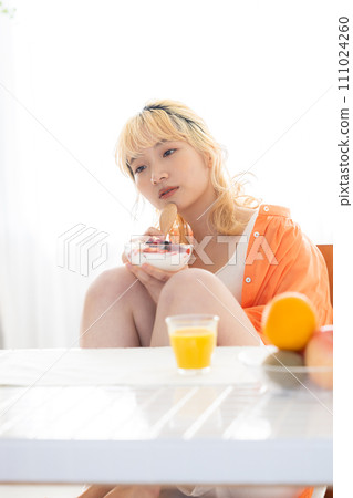 young blonde woman eating yogurt 111024260