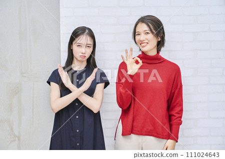 兩個女人做圓圈和十字架的手勢 兩個女人做圓圈和十字架的手勢 111024643