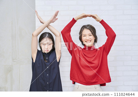 兩個女人做圓圈和十字架的手勢 兩個女人做圓圈和十字架的手勢 111024644