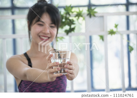 Woman drinking water hands holding cold mineral water cool drinking. Asian women smile laugh look away health care home fitness lifestyle. Cheerful Beautiful female drink glass of water smile face 111024761