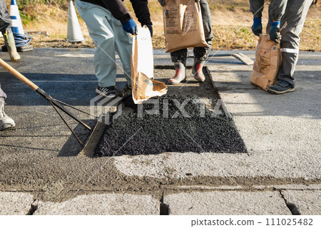 Road construction, asphalt pavement restoration work, leveling of room temperature mixture 111025482