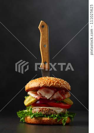 Fresh tasty burger with knife on a black background. 111025625