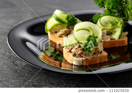 Open sandwiches with pate, fresh cucumber, capers, and parsley. 111025630
