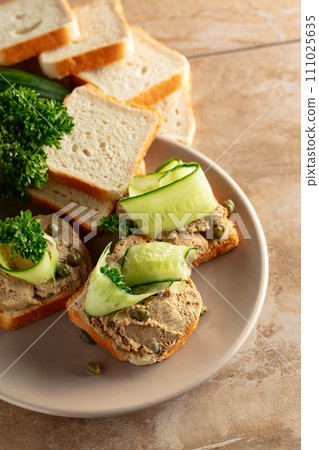 Open sandwiches with pate, cucumber, capers, and parsley. Open sandwiches with pate, cucumber, capers, and parsley. 111025635