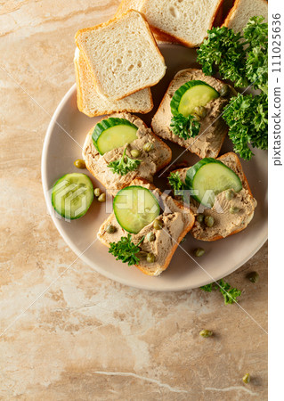 Open sandwiches with pate, cucumber, capers, and parsley. 111025636