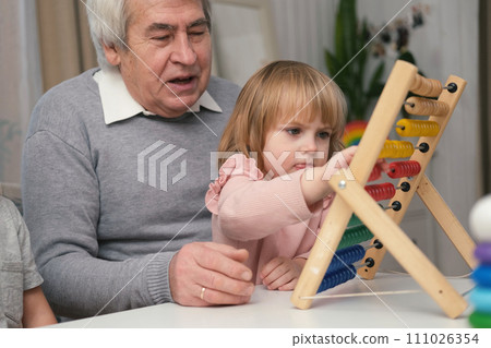 Grandfather playing toys with grandson and young granddaughter indoor. Old man grandpa studying with his grandchildren at weekend. Senior male having fun with kids. Happy multigeneration family video Grandfather playing toys with grandson and young granddaughter indoor. Old man grandpa studying with his grandchildren at weekend. Senior male having fun with kids. Happy multigeneration family video 111026354