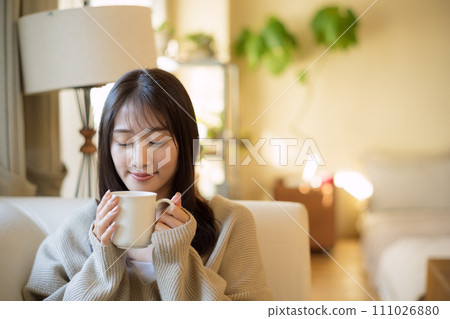 一個女人在沙發上放鬆地喝咖啡 一個女人在沙發上放鬆地喝咖啡 111026880