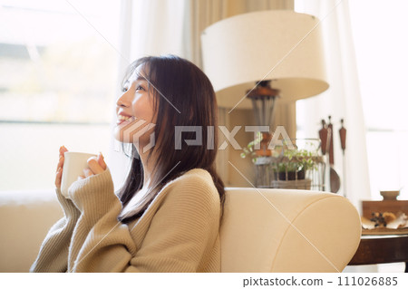 A woman drinking coffee while relaxing on a sofa 111026885