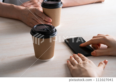 Hand touching smartphone while drinking a drink Hand touching smartphone while drinking a drink 111027041