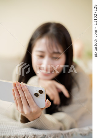 Woman using smartphone on bed Woman using smartphone on bed 111027129