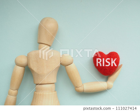 The word RISK is written on a red heart held by a mannequin. The word RISK is written on a red heart held by a mannequin. 111027414