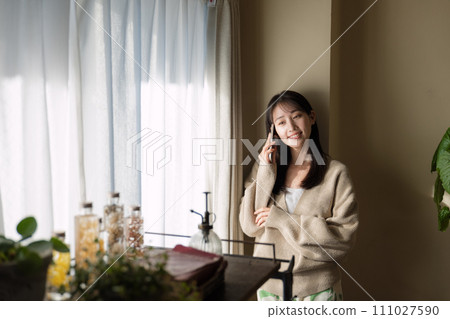 A woman talking on a mobile phone by the window 111027590