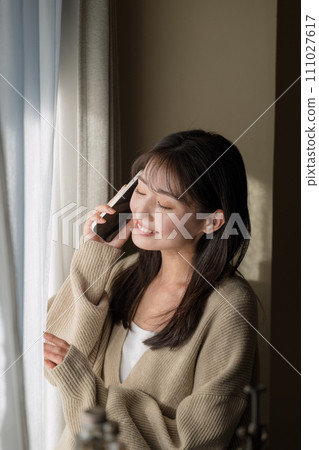 A woman talking on a mobile phone by the window 111027617