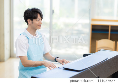 Male nursery teacher playing the piano Male nursery teacher playing the piano 111027627