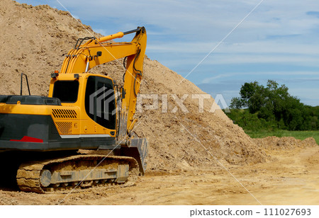 An excavator car and a pile of dirt in a road construction area. An excavator car and a pile of dirt in a road construction area. 111027693