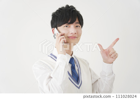 High school boy giving a zip sign while calling on a smartphone, white background High school boy giving a zip sign while calling on a smartphone, white background 111028024