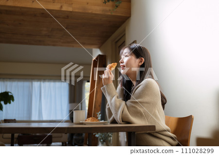 A woman enjoying a meal at the table in the living room 111028299