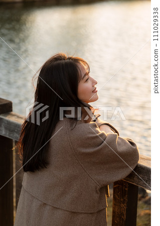 A woman walking in the city at sunset 111029338