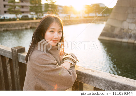 A woman walking in the city at sunset 111029344