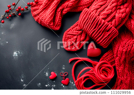 Red knitted scarf, hearts and snowflakes on black wooden background Red knitted scarf, hearts and snowflakes on black wooden background 111029956