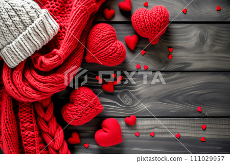 Red knitted scarf, hearts and snowflakes on black wooden background 111029957
