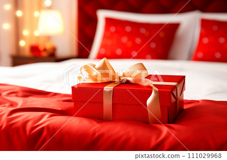 Red gift box with gold ribbon on bed decoration in hotel bedroom interior Red gift box with gold ribbon on bed decoration in hotel bedroom interior 111029968