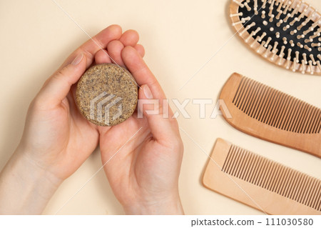 Solid shampoo in female hands. Natural eco-cosmetics without plastic for the hair care Solid shampoo in female hands. Natural eco-cosmetics without plastic for the hair care 111030580