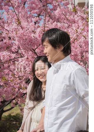 Couple cuddling in front of cherry blossoms 111030598
