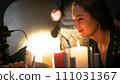 The woman stands intrigued by the candles  111031367