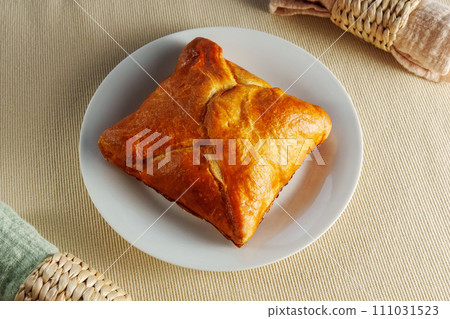 A visually stunning composition featuring a perfectly baked puff pastry adorning a pristine white plate. A visually stunning composition featuring a perfectly baked puff pastry adorning a pristine white plate. 111031523